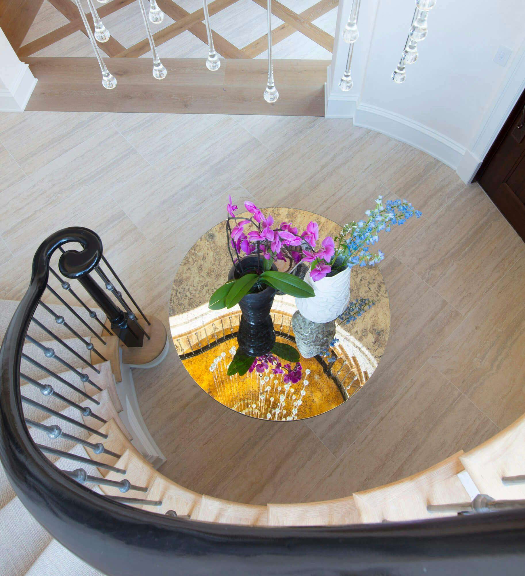 top view of a spiral staircase onto a reflective table with pink and blue flowers